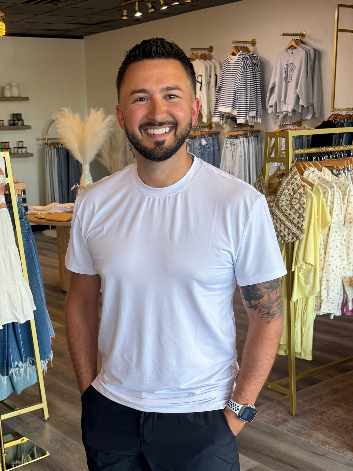 Man standing in a clothing store with racks of clothes in the background